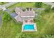 Aerial view of a home with a pool, patio, and lush green yard surrounded by mature trees at 10594 Geist Rd, Fishers, IN 46037