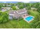 Aerial view of a home with a pool, patio, and three-car garage surrounded by lush greenery and trees at 10594 Geist Rd, Fishers, IN 46037