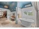 Airy bathroom with a freestanding tub, shuttered windows, bench seating, and blue painted ceiling at 10594 Geist Rd, Fishers, IN 46037