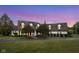 Two-story home featuring a red front door, mature trees, and a pristine lawn at dusk at 10594 Geist Rd, Fishers, IN 46037