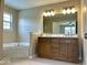 Bathroom featuring a wood vanity with double sinks and a soaking tub underneath a window at 11154 Schoolhouse Rd, Fishers, IN 46037