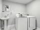 Well-lit laundry room featuring white front-load washer and dryer, with pedestal sink and marble flooring at 1151 S Randolph St, Indianapolis, IN 46203
