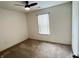 An empty bedroom with plush carpet, bright window, and a ceiling fan at 1706 Creekwater Pass, Greenfield, IN 46140