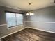 Dining room with wood-look floors, neutral gray walls, a chandelier, and bright window at 1706 Creekwater Pass, Greenfield, IN 46140