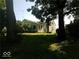 View of a lovely backyard with lush grass, mature trees, and a charming home in the background at 18378 Southeastern Pkwy, Fortville, IN 46040
