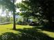 Exterior view of a cozy home with a wooden deck, complemented by the shade of lush trees at 18378 Southeastern Pkwy, Fortville, IN 46040