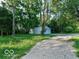 View of a white metal outbuilding with a garage door, gravel driveway and surrounded by a lush green lawn at 18378 Southeastern Pkwy, Fortville, IN 46040