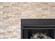 Close-up of a modern stone fireplace with a black mantle and logs at 2130 Brookside Pkwy N Dr, Indianapolis, IN 46201