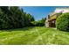 Spacious backyard featuring a well-manicured lawn, mature trees, and a glimpse of the home's exterior at 2411 N Willow Way, Indianapolis, IN 46268