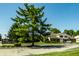 Exterior community shot with manicured lawn, mature tree, community sign, and residential buildings at 2411 N Willow Way, Indianapolis, IN 46268