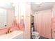 Stylish bathroom with pink tiles, gold fixtures, and shower with pink curtain at 2702 S Moreland Ave, Indianapolis, IN 46241