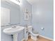 Powder room with light blue walls, white pedestal sink, and wooden-style floor at 3058 Mcintosh Dr, Bargersville, IN 46106
