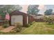 Detached garage in backyard with white door, and lawn with garden at 3422 Sycamore Dr, Columbus, IN 47203