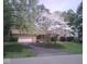 Quaint home featuring a stone facade, attached garage and driveway, set amidst blooming trees and lush greenery at 3813 N Ramsgate Rd, Martinsville, IN 46151