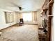 The bright living room features a brick fireplace, a ceiling fan, and a large window at 4096 N 200 W, Greenfield, IN 46140