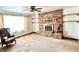 A spacious living room with a brick fireplace, a ceiling fan, and a large window at 4096 N 200 W, Greenfield, IN 46140