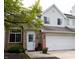 Charming townhome featuring a brick facade, white siding, attached garage and blossoming greenery at 5704 Carrousel Dr, Indianapolis, IN 46254