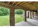 Charming outdoor patio featuring brick columns, a wooden ceiling, and a view of the lush green lawn at 7843 E Triple Crown Ln, Camby, IN 46113