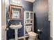 Cozy bathroom with a pedestal sink, a wooden-framed mirror, and blue accent wall, offering a serene space at 8125 Whistlewood Dr, Indianapolis, IN 46239