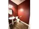 Powder room featuring wood-look floors, red walls, pedestal sink, and toilet at 9404 Crystal River Dr, Indianapolis, IN 46240
