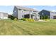 Beautifully landscaped backyard with green lawn, manicured shrubs, and a covered patio area at 9986 Gallop Ln, Fishers, IN 46040