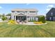Spacious backyard of a two-story home with lush green grass, landscaping, and a covered patio at 9986 Gallop Ln, Fishers, IN 46040