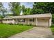 Inviting single-story home with a driveway leading to an attached garage, surrounded by lush green landscaping at 10155 Orchard Park W Dr, Carmel, IN 46280