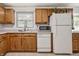 View of the kitchen featuring wood cabinets, white appliances, and a stainless steel sink under a window at 10155 Orchard Park W Dr, Carmel, IN 46280