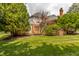 Backyard of home with brick chimney, well-manicured lawn, large trees, and deck at 14030 Old Mill Ct, Carmel, IN 46032