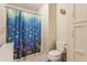 Small bathroom with a blue fish shower curtain, toilet, and storage cabinets at 14030 Old Mill Ct, Carmel, IN 46032