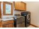 Bright laundry room with modern washer, dryer, and wood cabinets above the sink at 14030 Old Mill Ct, Carmel, IN 46032