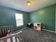 A cozy green bedroom with a window, crib and white storage unit on top of soft gray carpet at 1406 Bigleaf Cir, Sheridan, IN 46069