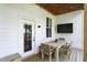 Cozy covered patio features a wooden table, wicker chairs, and a mounted television at 1406 Linden St, Indianapolis, IN 46203
