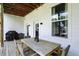 Relaxing covered patio with grill, wooden table, wicker chairs, and natural light at 1406 Linden St, Indianapolis, IN 46203