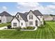 Beautifully landscaped two-story home with white brick, dark trim, and lush green lawn at 16283 Spring Bank Ct, Fishers, IN 46040