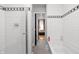 Bright bathroom boasting classic white tile walls with black accent trim, shower with glass doors, and a view into the bedroom at 207 S Meridian St # 2F, Indianapolis, IN 46225