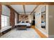 Cozy bedroom with exposed brick, wood beam accents, a modern bed, and ample natural light at 207 S Meridian St # 2F, Indianapolis, IN 46225