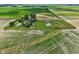 Wide aerial shot of a well-kept rural property featuring multiple buildings and fenced yard at 26735 Six Points Rd, Sheridan, IN 46069