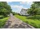 Exterior view of a white home with a long driveway, surrounded by mature trees on a sunny day at 26735 Six Points Rd, Sheridan, IN 46069