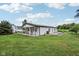 Rear view of the white home with a covered patio area and spacious lawn, blending rural charm and comfort at 26735 Six Points Rd, Sheridan, IN 46069