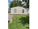 View of the back exterior featuring neutral siding, green trim, and a partially paved yard at 3059 5Th E Ave, Indianapolis, IN 46221