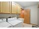 A laundry room with neutral walls, a washing machine, dryer, sink, and wood cabinets at 3920 Oak Harbor Ln, Indianapolis, IN 46237