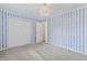 Bedroom with blue striped wallpaper features neutral carpet and a double door closet at 421 E Delaware St, Fortville, IN 46040