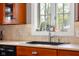 Close-up of kitchen sink featuring tile backsplash, quartz countertops, and window view at 4224 River Rd, Columbus, IN 47203