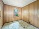 Bedroom with paneling, a window overlooking the exterior, and floor in need of repair at 4708 Fletcher Ave, Indianapolis, IN 46203