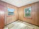 Bedroom featuring paneling, two windows overlooking the exterior, and worn floors at 4708 Fletcher Ave, Indianapolis, IN 46203