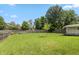 Large, grassy backyard with a wooden fence, shed, and mature trees under a clear blue sky at 59 Millet Ct, Danville, IN 46122
