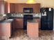 Well-lit kitchen with wood cabinets, dark countertops, mosaic backsplash, and black appliances at 7532 Gold Rush Ct, Camby, IN 46113