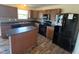Kitchen featuring wood cabinets, dark countertops, mosaic backsplash, island, and black appliances at 7532 Gold Rush Ct, Camby, IN 46113
