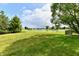 Expansive grassy backyard with view of a serene pond and surrounding neighborhood homes in the distance at 10548 Magenta Dr, Noblesville, IN 46060